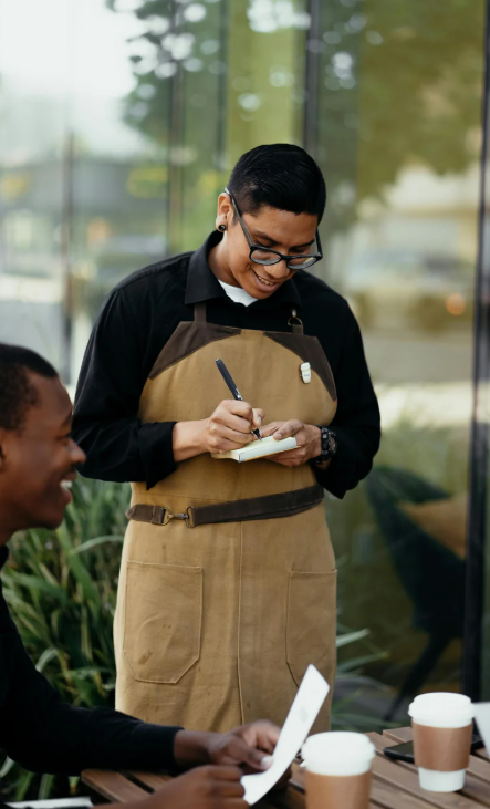 Server taking an order on a notepad at a café table